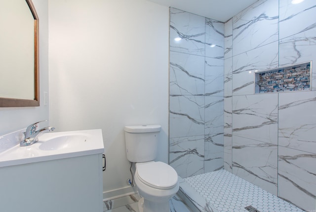 bathroom featuring vanity, toilet, and a tile shower