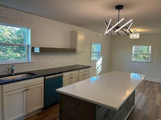 kitchen with dishwashing machine, hanging light fixtures, dark wood-type flooring, and sink