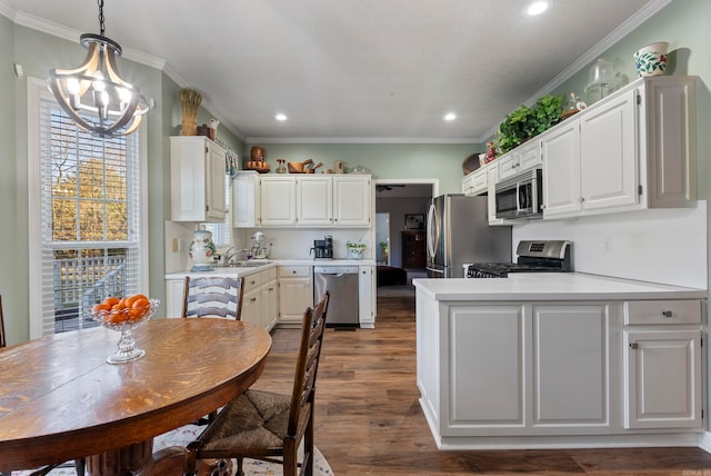 kitchen featuring crown molding, dark hardwood / wood-style floors, appliances with stainless steel finishes, decorative light fixtures, and white cabinetry