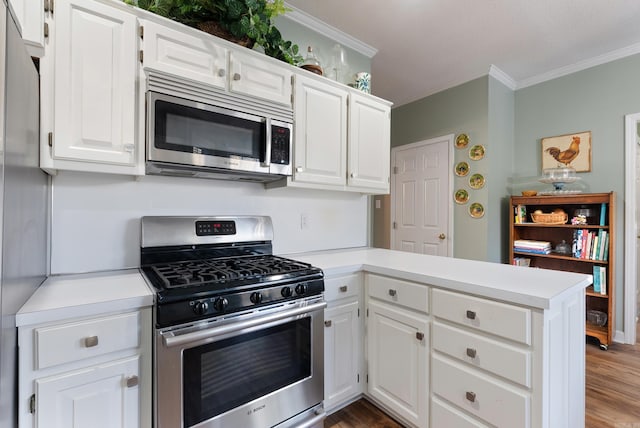 kitchen featuring white cabinets, ornamental molding, appliances with stainless steel finishes, dark hardwood / wood-style flooring, and kitchen peninsula