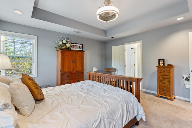 bedroom with a raised ceiling and light carpet