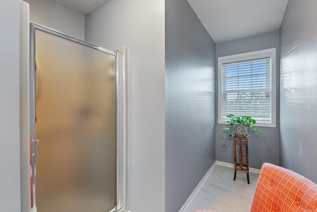 bathroom featuring a textured ceiling and a shower with shower door