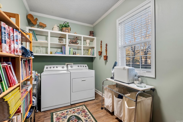 laundry room with washing machine and clothes dryer, light hardwood / wood-style floors, a textured ceiling, and ornamental molding