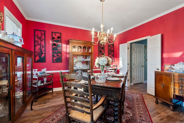 dining room featuring dark wood-type flooring, a notable chandelier, and ornamental molding