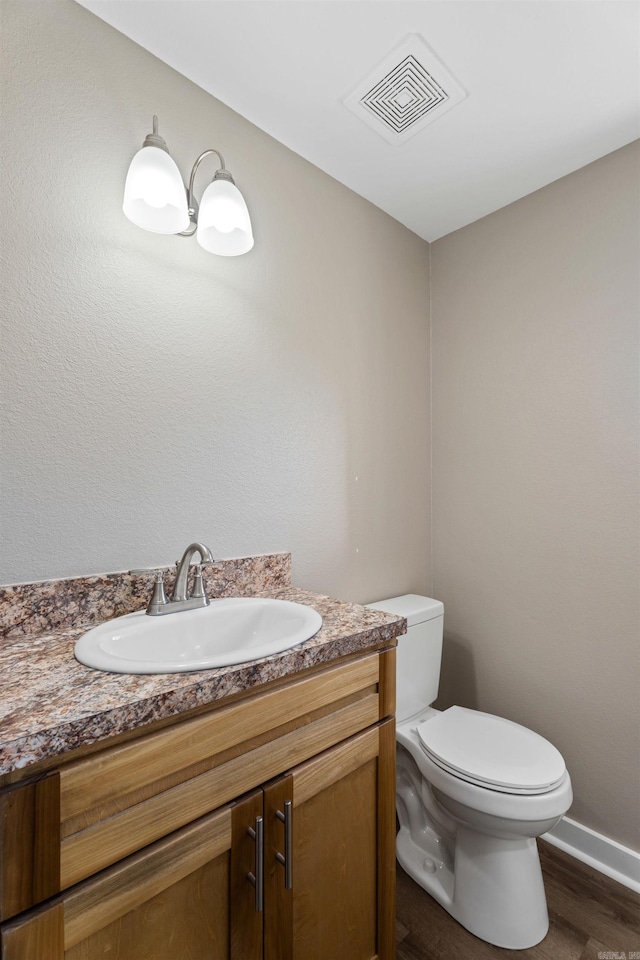 bathroom with toilet, vanity, and hardwood / wood-style flooring