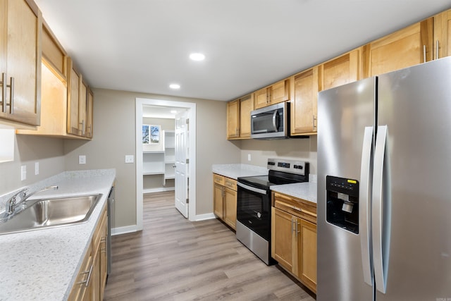 kitchen featuring light brown cabinets, sink, light hardwood / wood-style flooring, light stone countertops, and appliances with stainless steel finishes