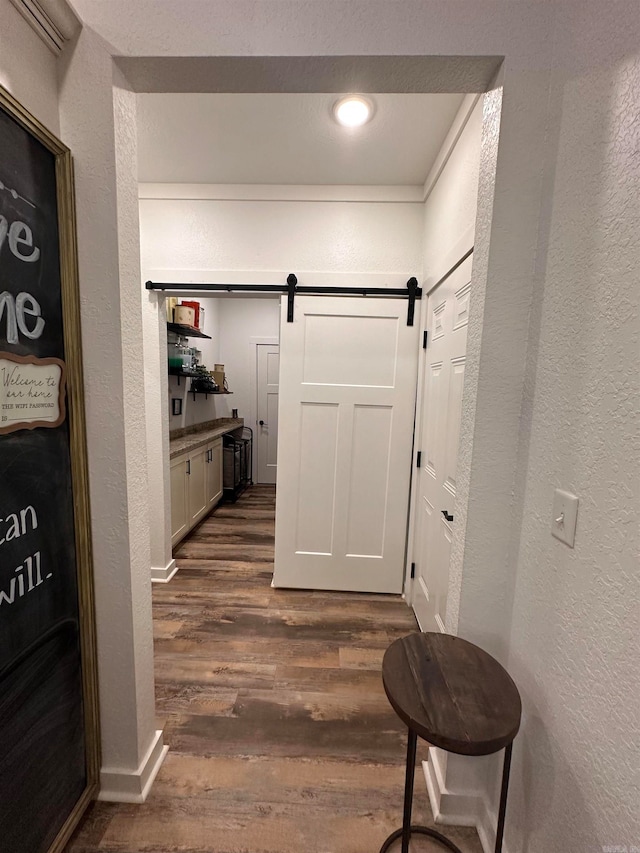 hallway featuring a barn door and dark wood-type flooring