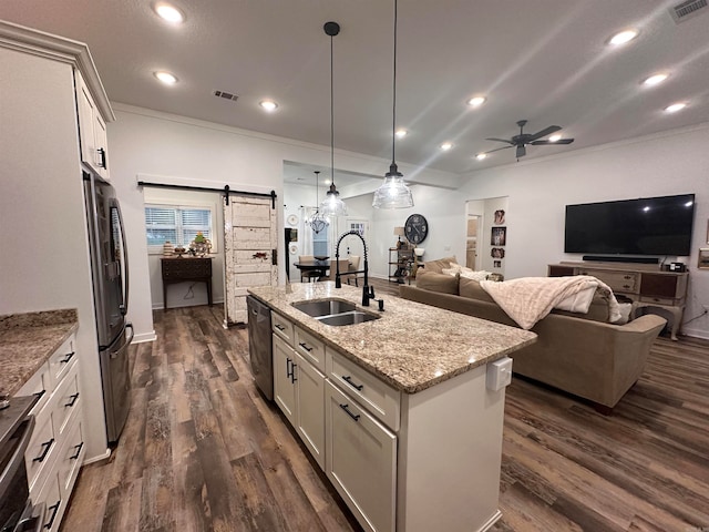 kitchen featuring white cabinetry, sink, a barn door, an island with sink, and decorative light fixtures