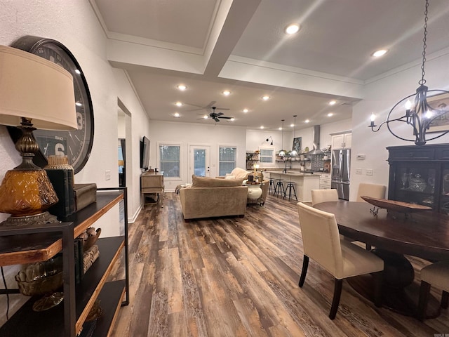 living room featuring beam ceiling, dark hardwood / wood-style flooring, and ceiling fan with notable chandelier