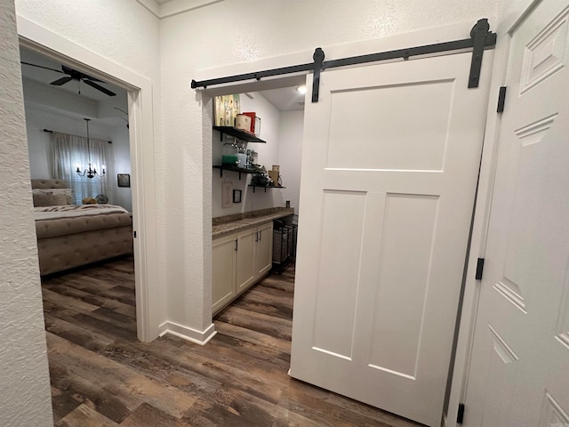 hallway with a barn door and dark hardwood / wood-style flooring