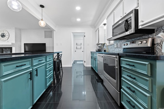 kitchen with green cabinets, crown molding, hanging light fixtures, a brick fireplace, and stainless steel appliances