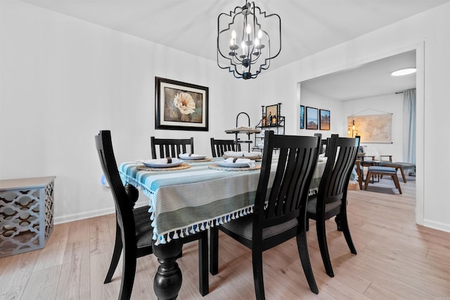 dining area featuring light wood-type flooring and a notable chandelier