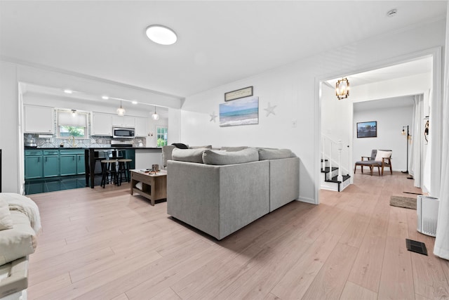 living room with light hardwood / wood-style floors and a notable chandelier