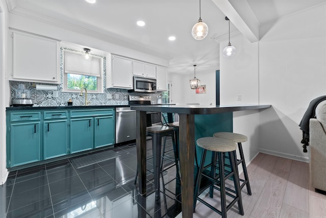 kitchen featuring stainless steel appliances, blue cabinets, backsplash, pendant lighting, and white cabinets