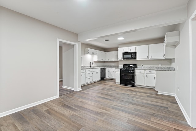 kitchen featuring black appliances, sink, light stone countertops, white cabinetry, and wood-type flooring