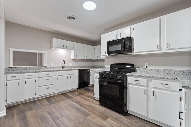 kitchen featuring white cabinetry, sink, light stone counters, dark hardwood / wood-style flooring, and black appliances