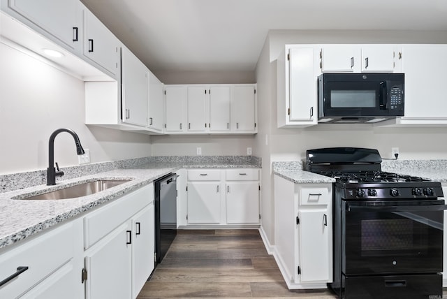 kitchen with light stone countertops, dark hardwood / wood-style flooring, sink, black appliances, and white cabinetry