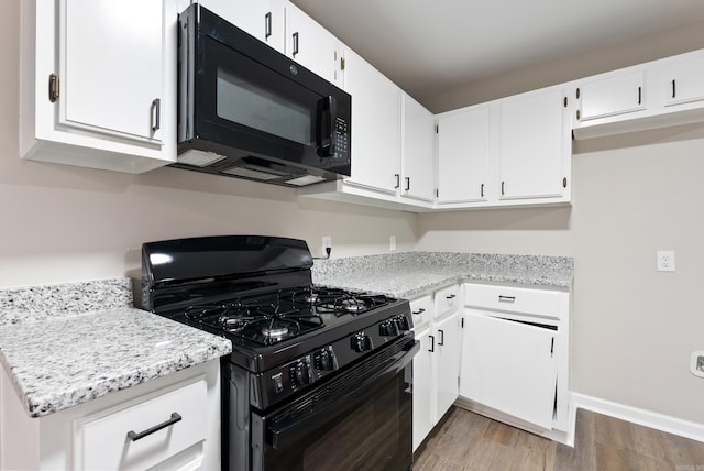 kitchen featuring black appliances, light hardwood / wood-style floors, white cabinets, and light stone counters