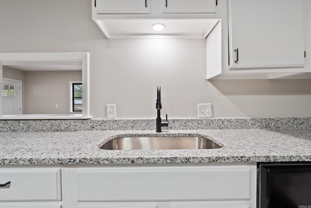 kitchen featuring white cabinets, light stone counters, and sink