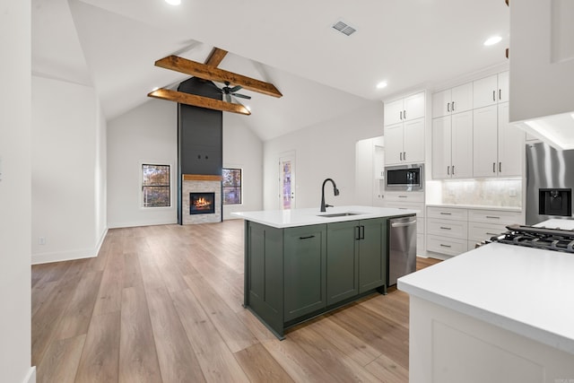 kitchen with light hardwood / wood-style floors, sink, lofted ceiling with beams, and appliances with stainless steel finishes