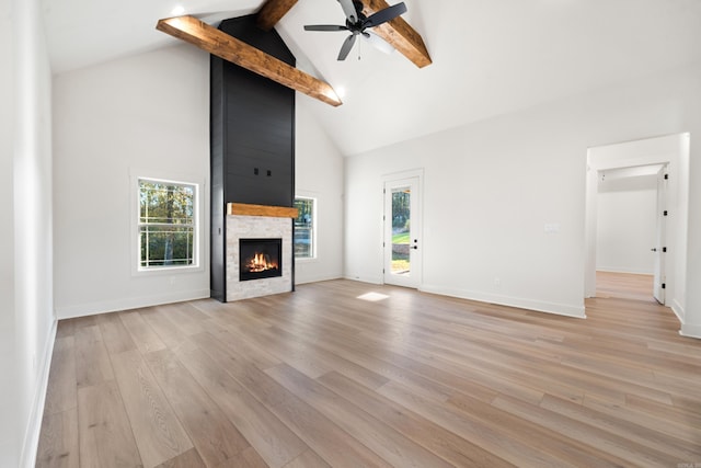 unfurnished living room with beamed ceiling, light hardwood / wood-style floors, and a healthy amount of sunlight