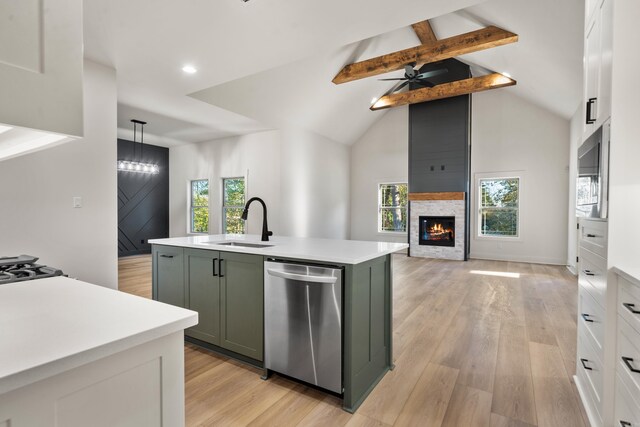 kitchen featuring white cabinetry, stainless steel dishwasher, plenty of natural light, an island with sink, and decorative light fixtures