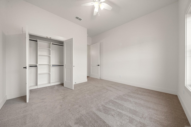 unfurnished bedroom with ceiling fan, light carpet, and a closet