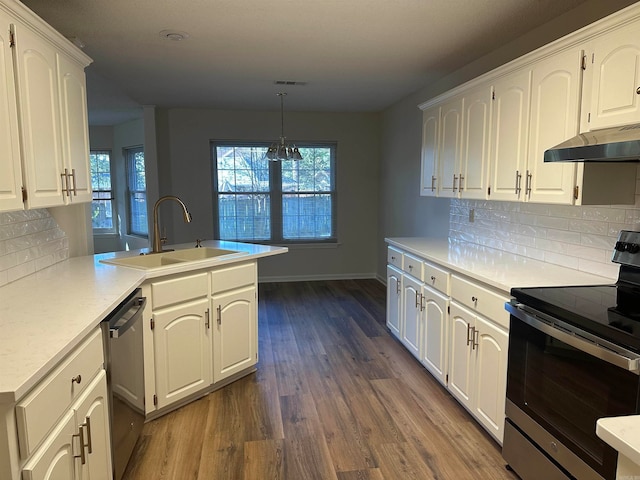 kitchen with kitchen peninsula, appliances with stainless steel finishes, sink, decorative light fixtures, and white cabinetry