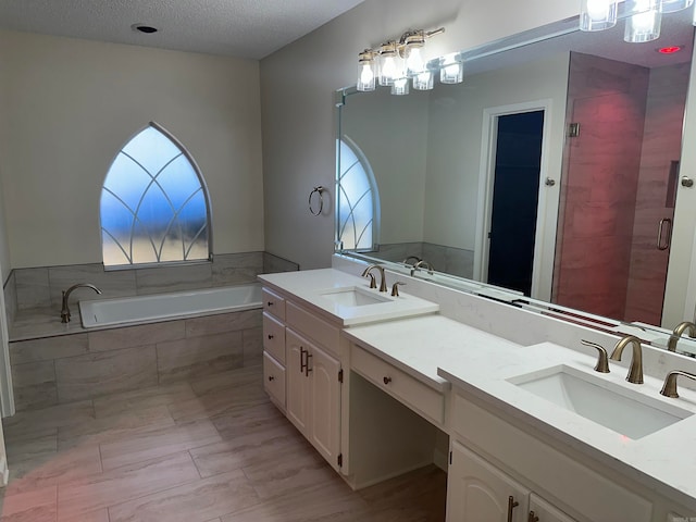 bathroom with vanity, a textured ceiling, and shower with separate bathtub