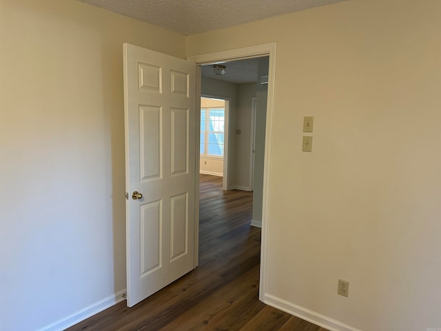 empty room featuring a textured ceiling and dark wood-type flooring