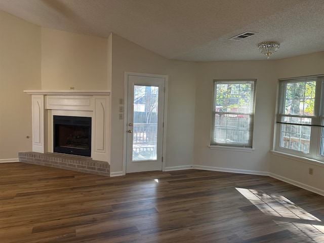 unfurnished living room with plenty of natural light, dark hardwood / wood-style floors, and a textured ceiling