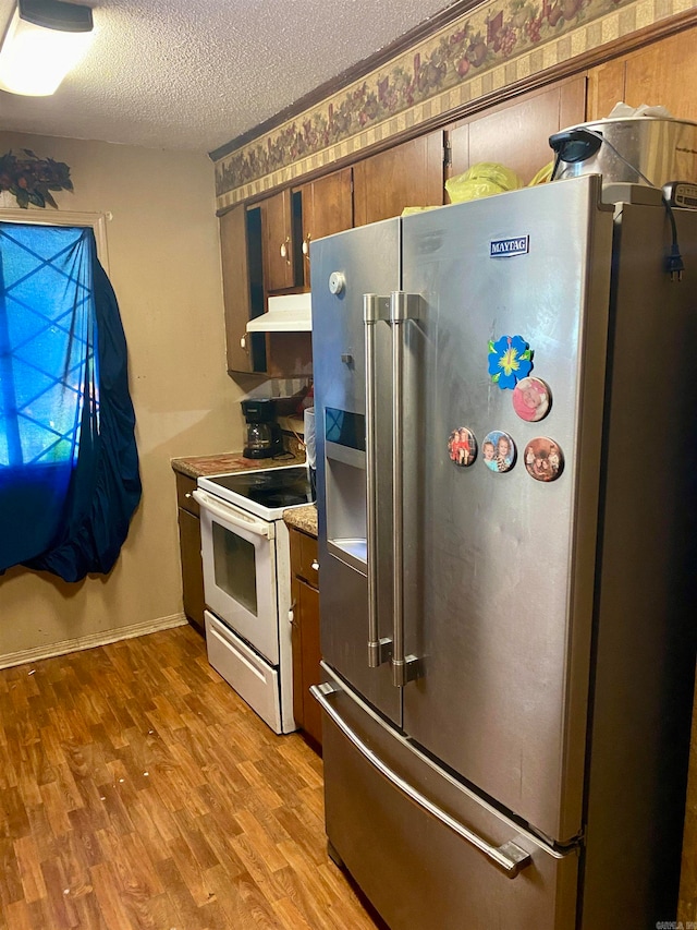 kitchen featuring light wood-type flooring, a textured ceiling, electric range, and high quality fridge