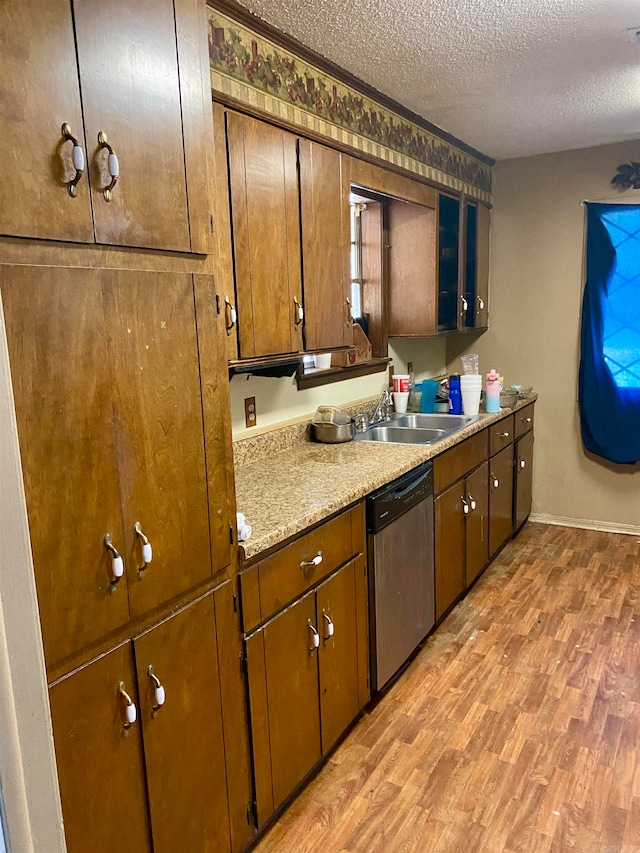 kitchen with dishwasher, light hardwood / wood-style floors, sink, and a textured ceiling