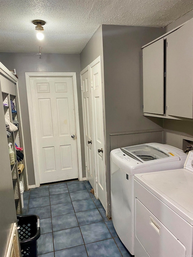 washroom featuring washer and clothes dryer, cabinets, a textured ceiling, and dark tile patterned flooring