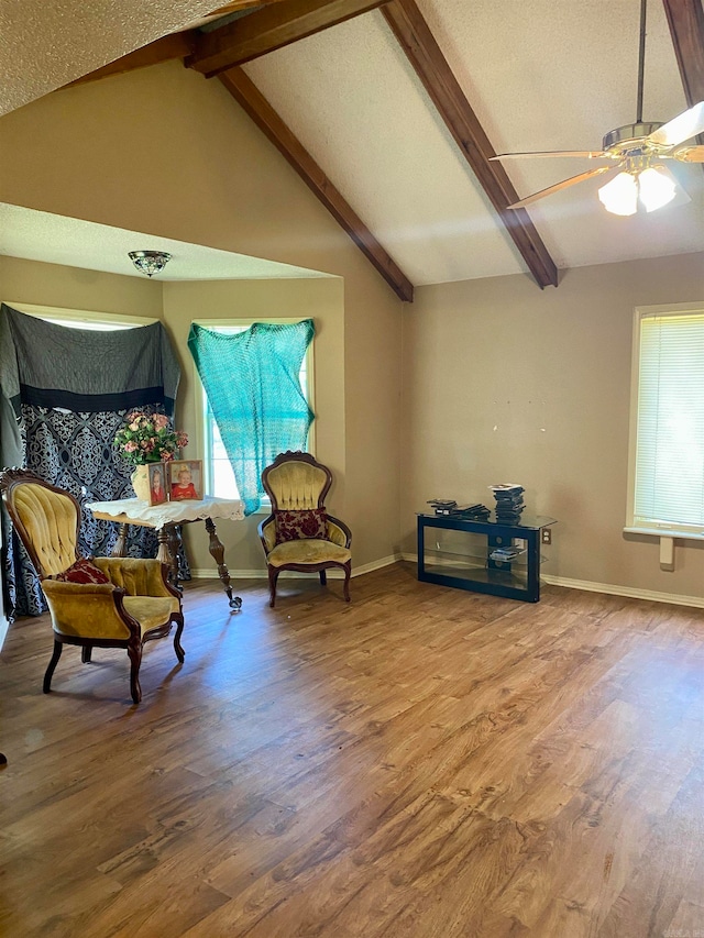 living area with ceiling fan, lofted ceiling with beams, and hardwood / wood-style flooring