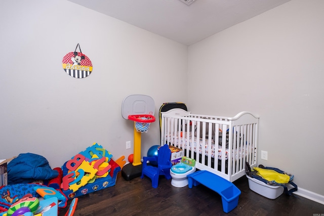 bedroom featuring a nursery area and wood-type flooring