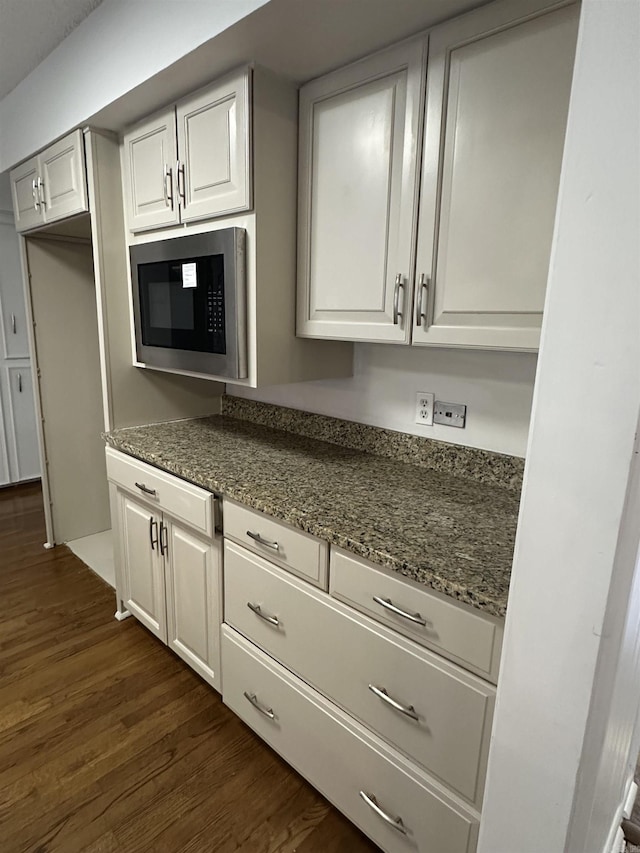 125 Pebble Beach Dr, Little Rock, AR 72212 - kitchen featuring built in microwave, dark wood finished floors, dark stone countertops, and white cabinets