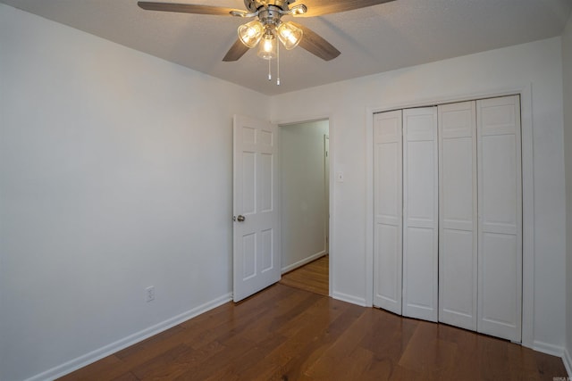 unfurnished bedroom with ceiling fan, a closet, and dark wood-type flooring