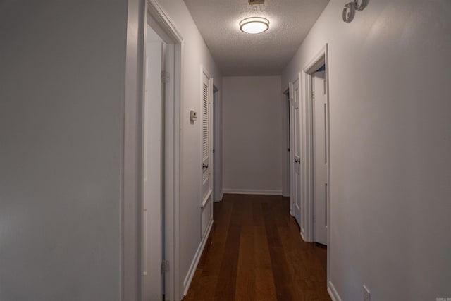 hall featuring dark wood-type flooring and a textured ceiling