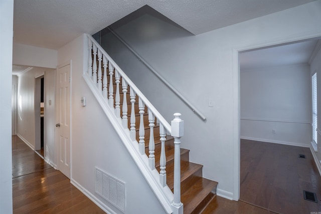 stairs featuring a textured ceiling and hardwood / wood-style flooring