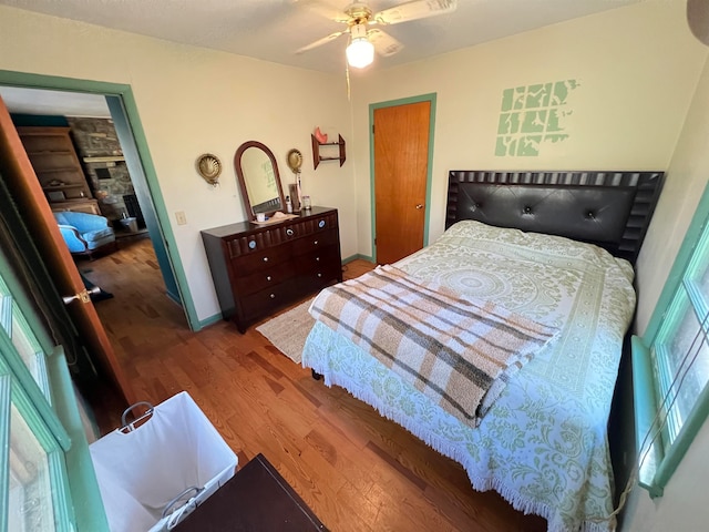 bedroom with multiple windows, ceiling fan, and hardwood / wood-style flooring