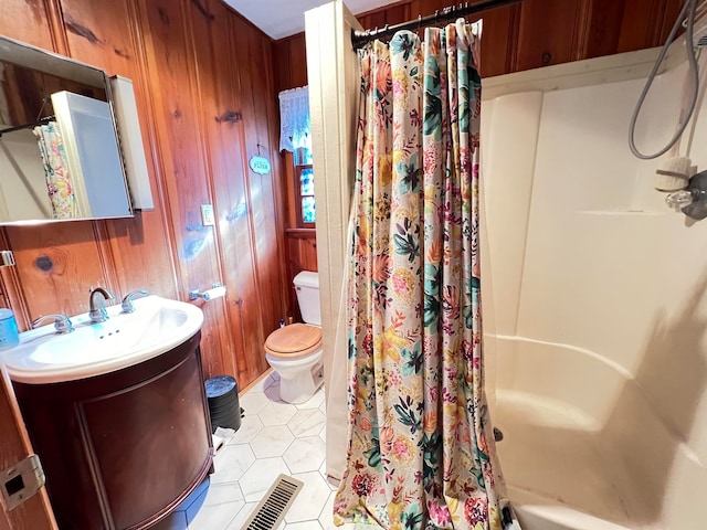 full bathroom with tile patterned floors, vanity, shower / tub combo with curtain, wooden walls, and toilet