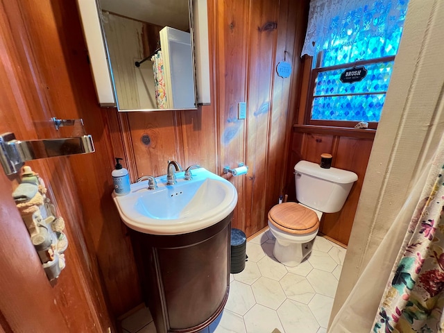 bathroom with tile patterned floors, vanity, toilet, curtained shower, and wood walls