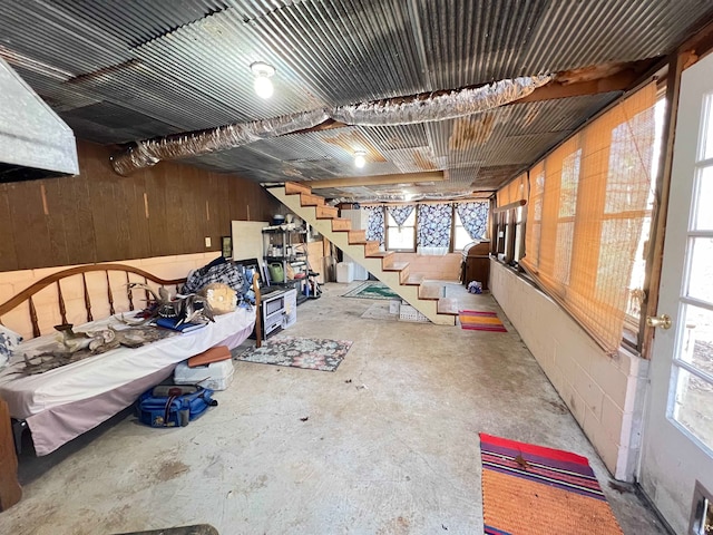 miscellaneous room with a wealth of natural light, concrete floors, and wood walls