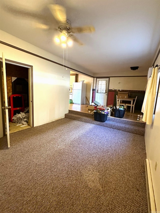 unfurnished living room featuring carpet flooring, a baseboard radiator, and ceiling fan