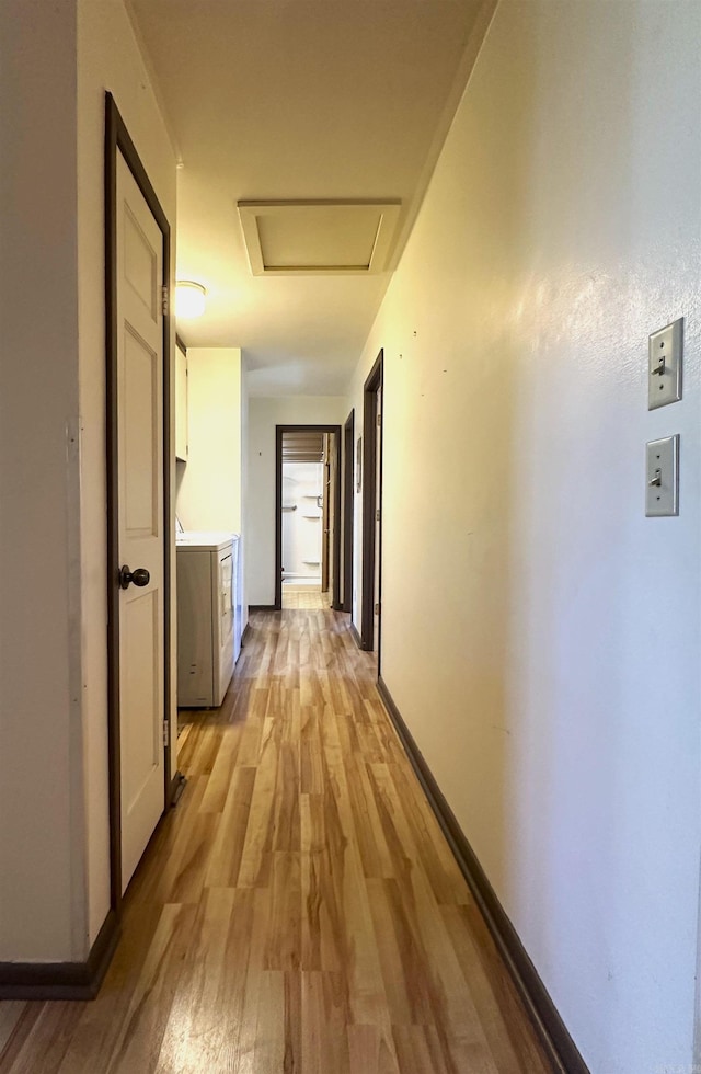 hallway with light hardwood / wood-style flooring and washer / dryer