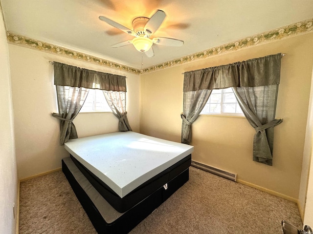 carpeted bedroom featuring baseboard heating, multiple windows, and ceiling fan