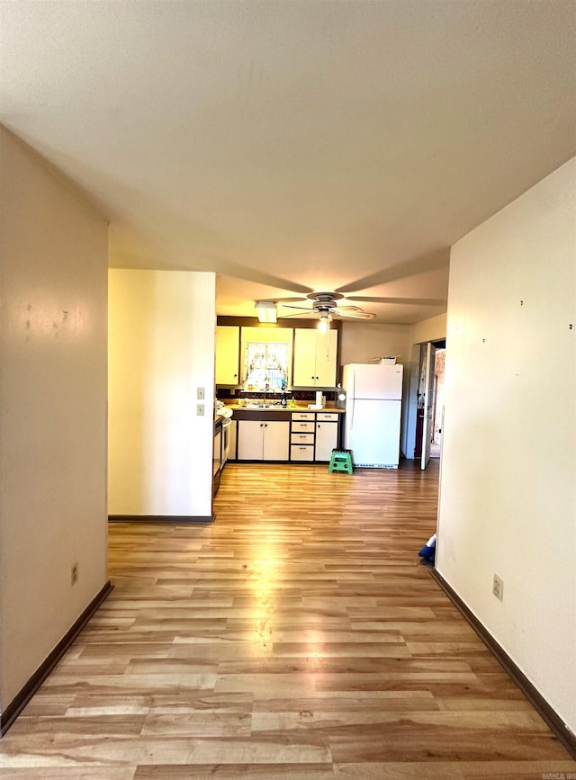 unfurnished living room featuring ceiling fan, sink, and light hardwood / wood-style flooring