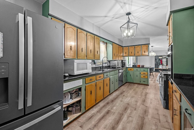 kitchen featuring appliances with stainless steel finishes, sink, pendant lighting, an inviting chandelier, and light hardwood / wood-style floors