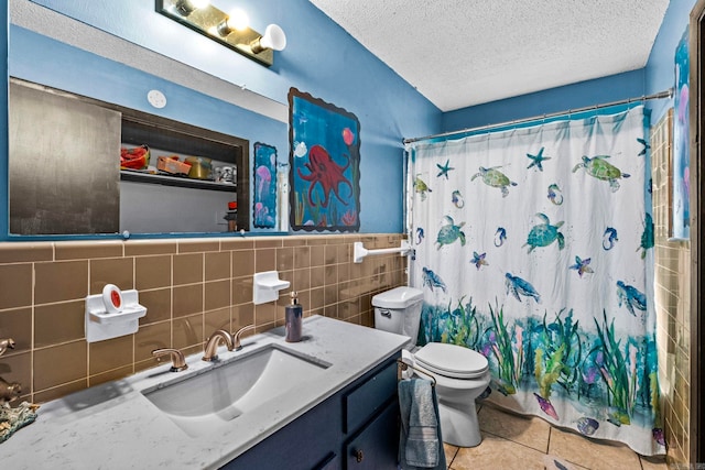 full bathroom featuring vanity, a textured ceiling, tile walls, tile patterned flooring, and toilet